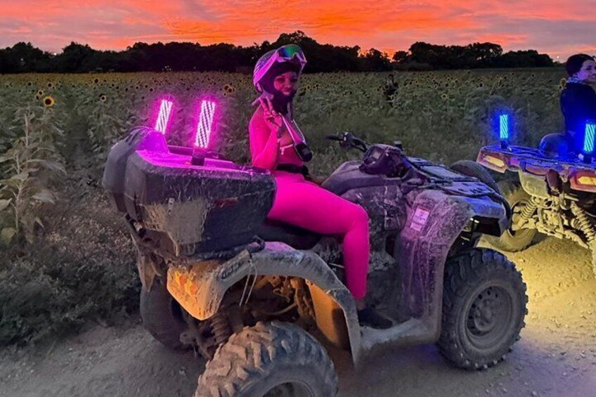 Una persona en un cuatrimoto con luces de neón, en un campo de girasoles. 1