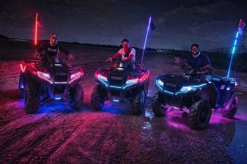 Tres cuatrimotos con luces encendidas y banderines, estacionadas en un camino de tierra. 5