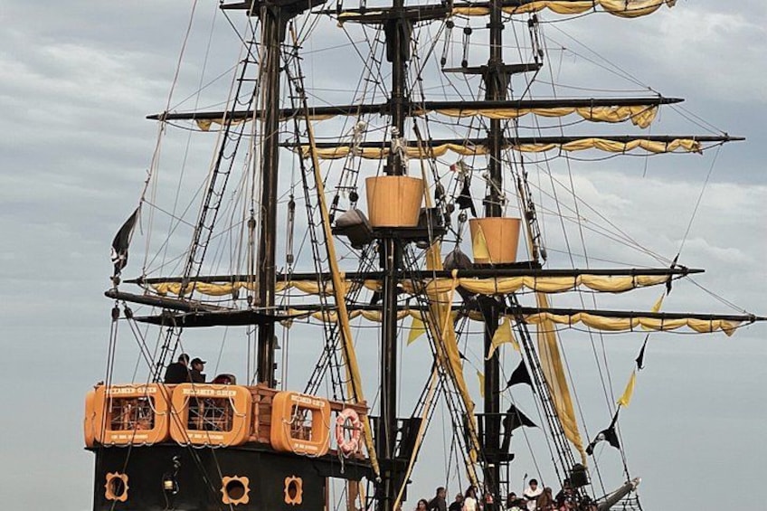 A tall ship with multiple masts and rigging, a crow's nest, and a cabin with a name 'DOLLY'. 4