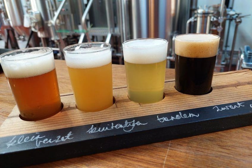 Quatre verres de bière sur un plateau en bois, chacun portant une étiquette. 4