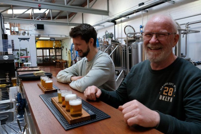 Deux personnes sont assises au bar, devant des verres de bière et une tireuse à bière. 3