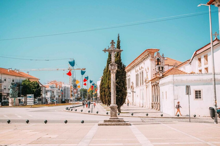 Una plaza con una fuente central, edificios blancos de techos rojos y banderas coloridas. 5