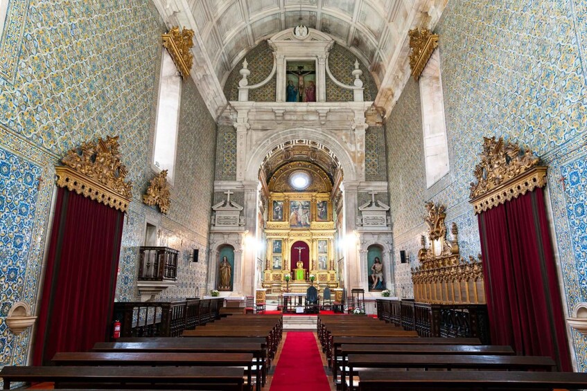 Interior de iglesia ornamentado con un pasillo de alfombra roja, altares dorados y paredes con un diseño azul y blanco. 3