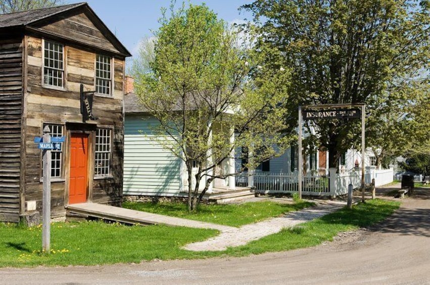 A wooden building with a red door, a sign for 'INSURANCE,' and a blue street sign. 3