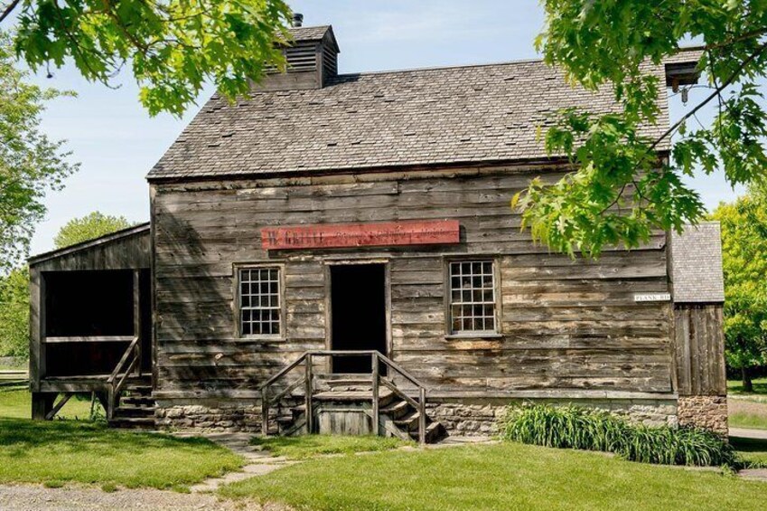 A rustic wooden building with a red sign, a staircase, and a grassy area. 1