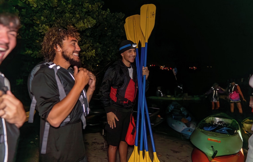 Des personnes avec des kayaks, dont un kayak vert, sur une plage, de nuit. 4