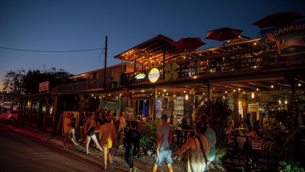 Un bar animé avec une terrasse et une enseigne représentant des bananes. 5