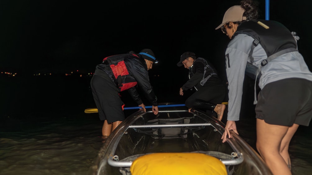 Un groupe de personnes aide une personne allongée sur une civière près d’un plan d’eau, la nuit. 3