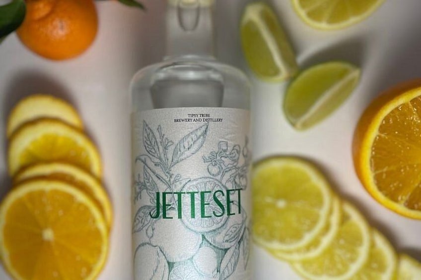 A bottle of JetteSet with a botanical design, surrounded by sliced oranges and lemons. 3