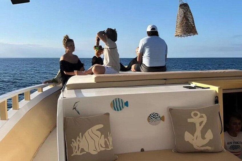 A boat with people on deck, a clear sky, and calm sea. 4