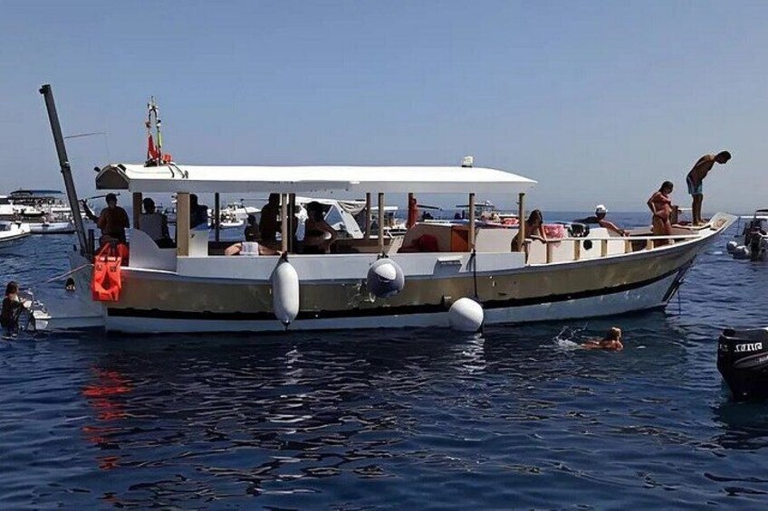A boat with people on board, docked in a marina with other boats. 2