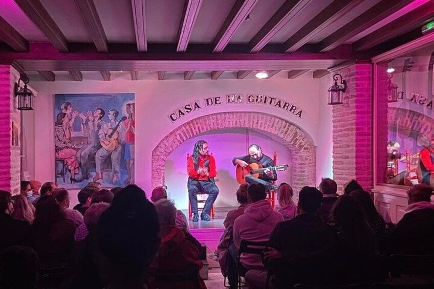 Un concert à la CASA DE LA GUITARRA, avec un artiste sur scène et un public assis devant. 3