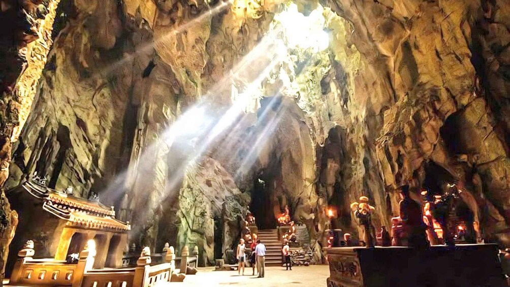 A cave with stalactites, a temple-like structure, and people inside. 2