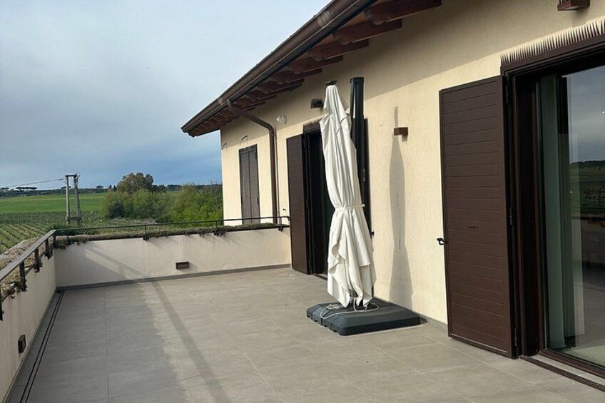 A rooftop terrace with a white umbrella, a brown door, and a view of the countryside. 4