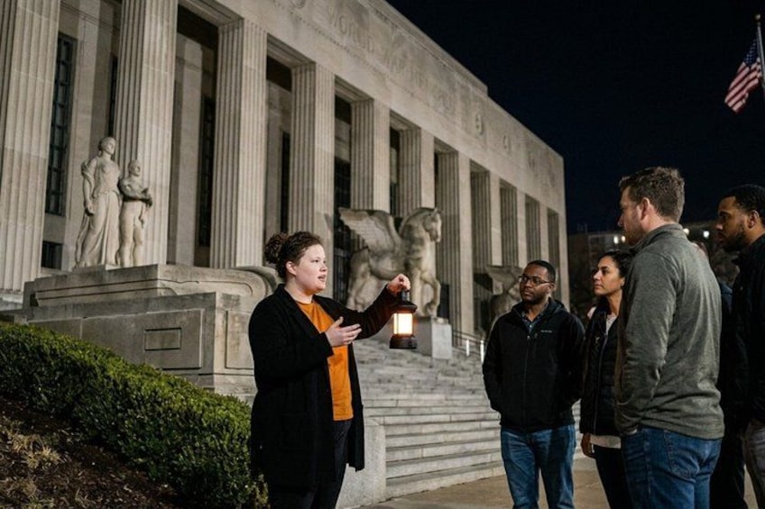 Un grupo de personas de pie frente a un edificio con arquitectura clásica, incluyendo columnas y estatuas. 3