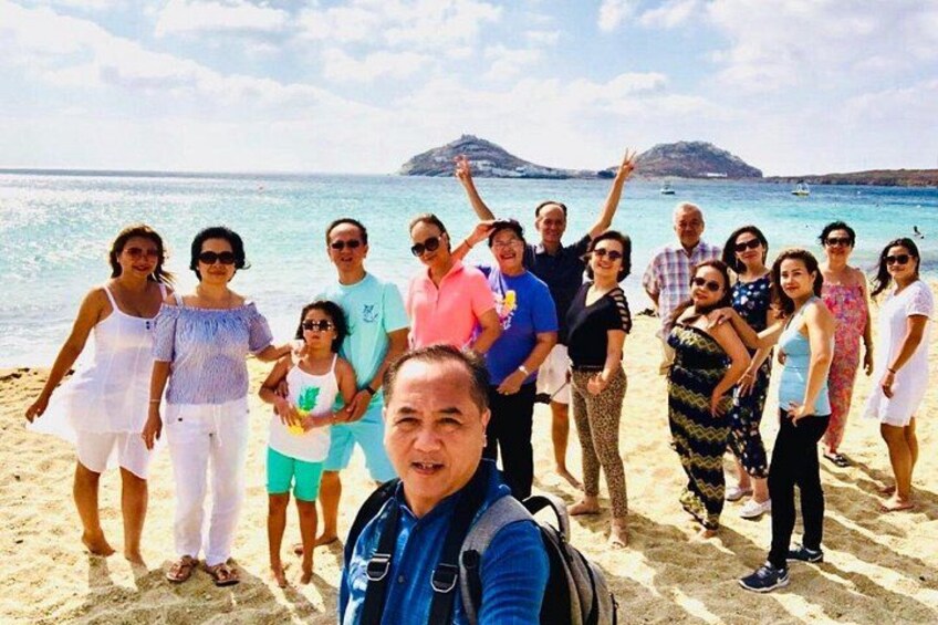 Un groupe de personnes se trouve sur une plage, avec la mer et une montagne en arrière-plan. 4