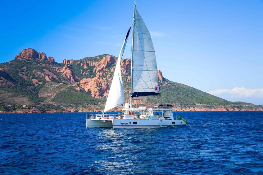 A sailboat named 'Ninah II' on the water with a mountainous landscape in the background. 3
