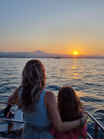 A sunset over a body of water with mountains in the background. 1