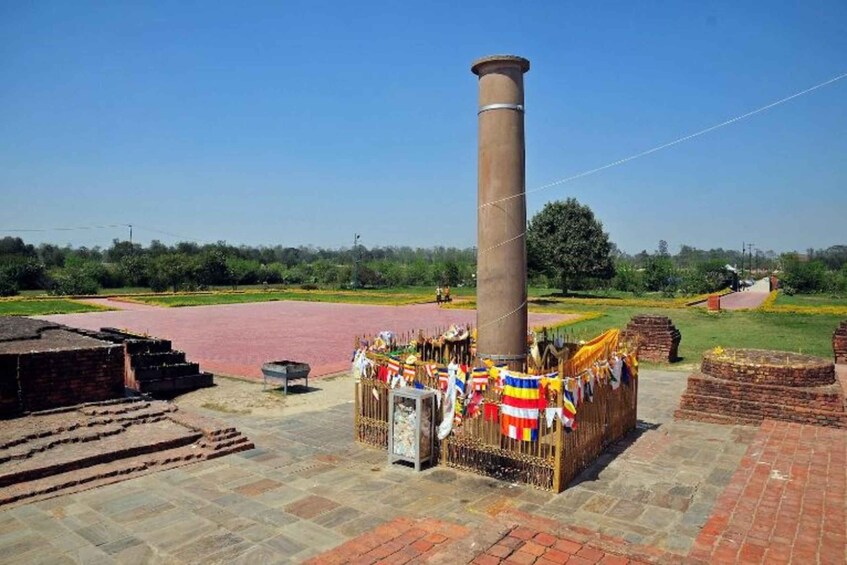 A historical site with a tall chimney, brick structures, and a paved area with flags. 2