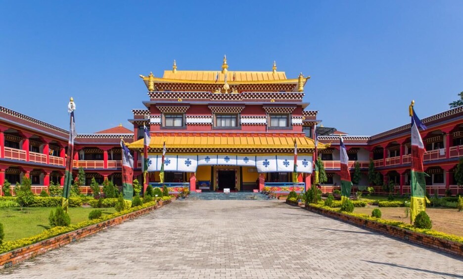 A traditional multi-tiered building with a golden roof, surrounded by a well-maintained garden and flags. 4
