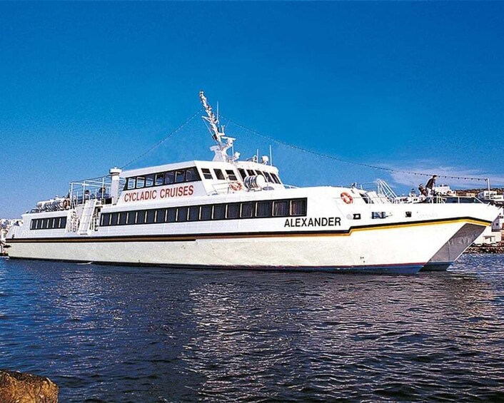 A large white cruise ship named 'ALEXANDER' with 'CYCLADIC CRUISES' written on its side, docked at a port with calm waters and clear skies. 2