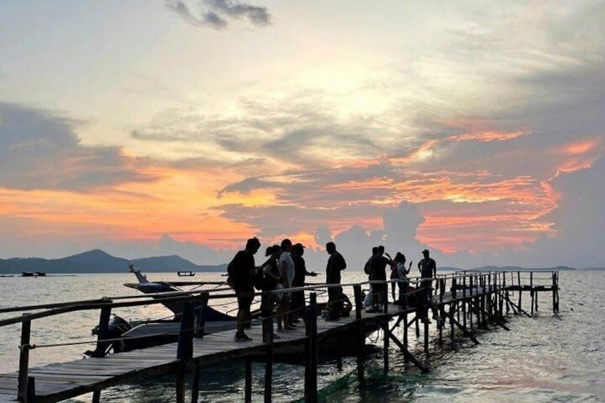 A sunset over a body of water with a pier and people standing on it. 4