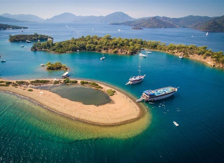 A coastal area with clear turquoise waters, several boats, and a small island with a sandy beach. 2