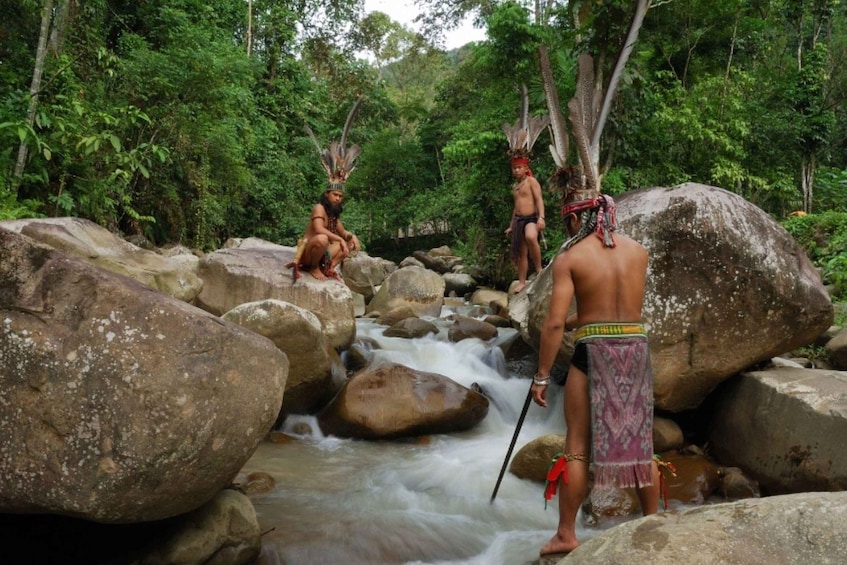 A river flowing over rocks with individuals wearing traditional attire and headdresses. 2