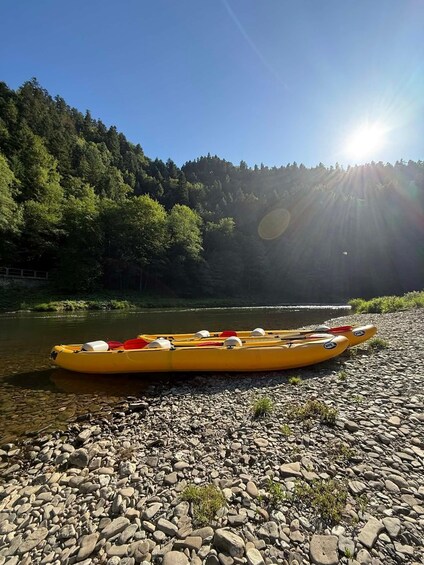 A yellow kayak on a rocky riverbank with a forested hillside in the background. 3