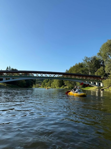 A river with kayaks, a bridge, and trees. 2