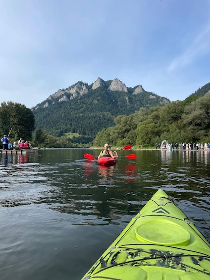 A group kayaking on a calm lake with mountains in the background. 1