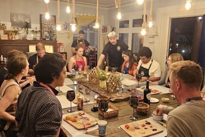 A group of people dining around a table with various dishes and drinks. 5