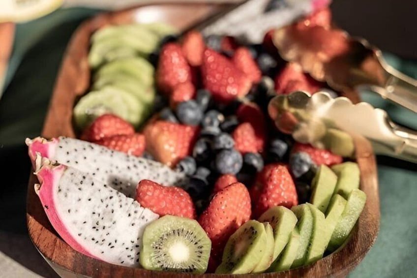 A wooden board with sliced kiwi, strawberries, blueberries, dragon fruit, and avocado. 3