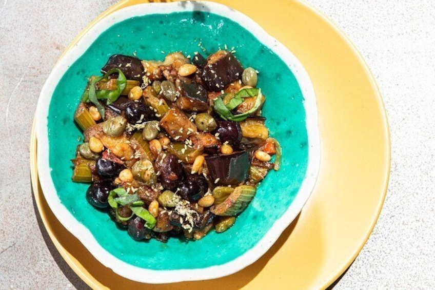 A bowl of food with vegetables and chickpeas on a yellow plate. 1