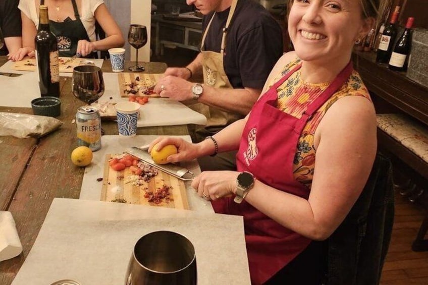 A person in a red apron preparing food at a wooden table with a cutting board, a knife, and a can of Fresca. 2
