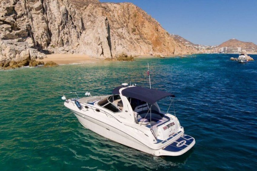 A white motorboat with a canopy on a calm sea, rocky cliffs, and a clear sky in the background. 3