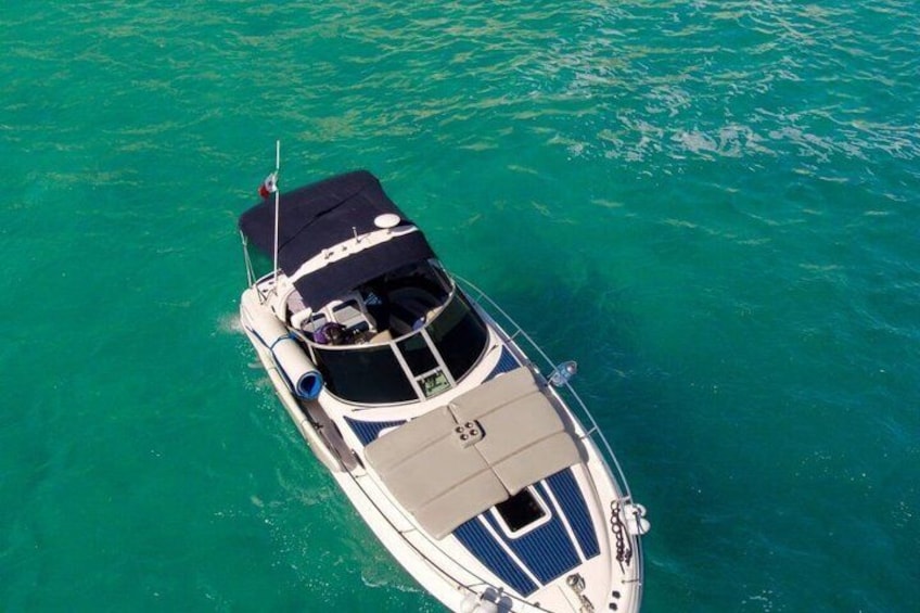 A boat with a cabin and a flag on top, floating on turquoise water. 4
