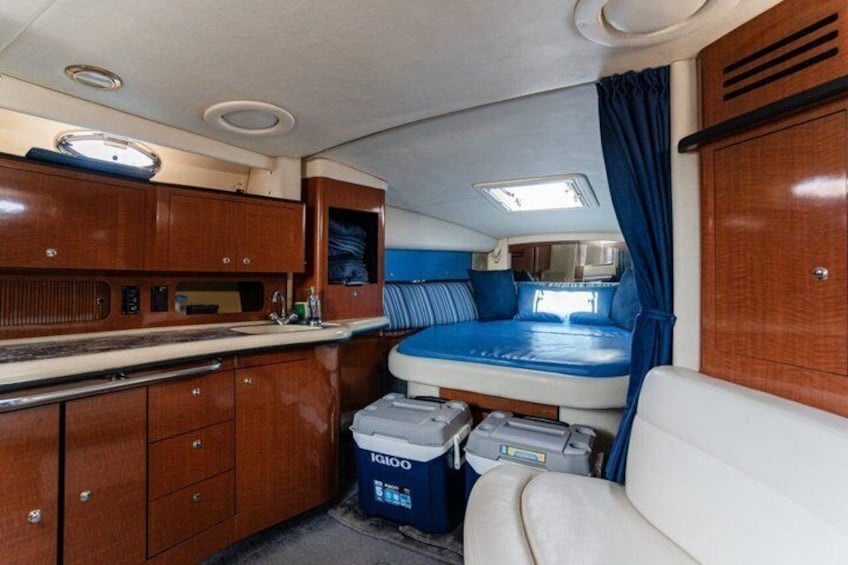 A compact RV interior with a kitchenette, a bed, and storage cabinets. 2