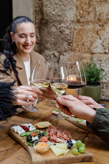 A group of people toasting with wine glasses at a wooden table with a charcuterie board. 5
