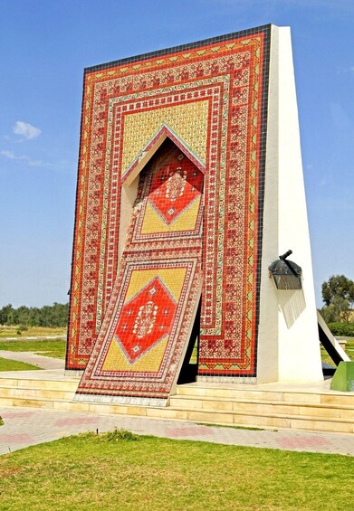 A large, intricately patterned wall with a central archway, set against a clear blue sky. 3
