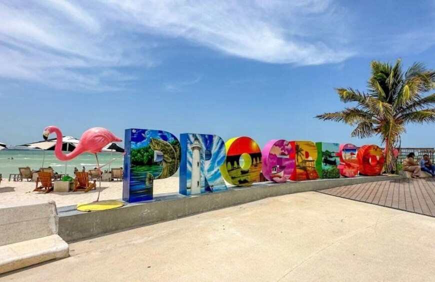A beach with colorful letters spelling 'PICTURE' and a flamingo sculpture. 3
