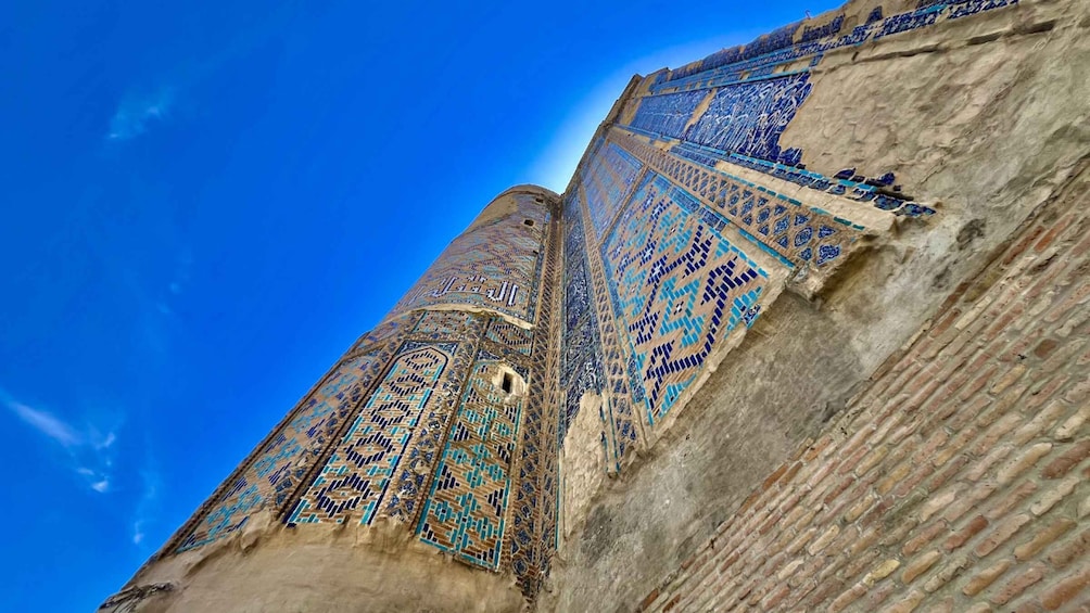 A tall, intricately patterned minaret with blue and beige tiles against a clear blue sky. 4
