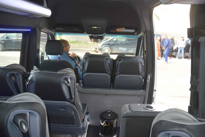 The interior of a vehicle with multiple seats and a cup holder. 1