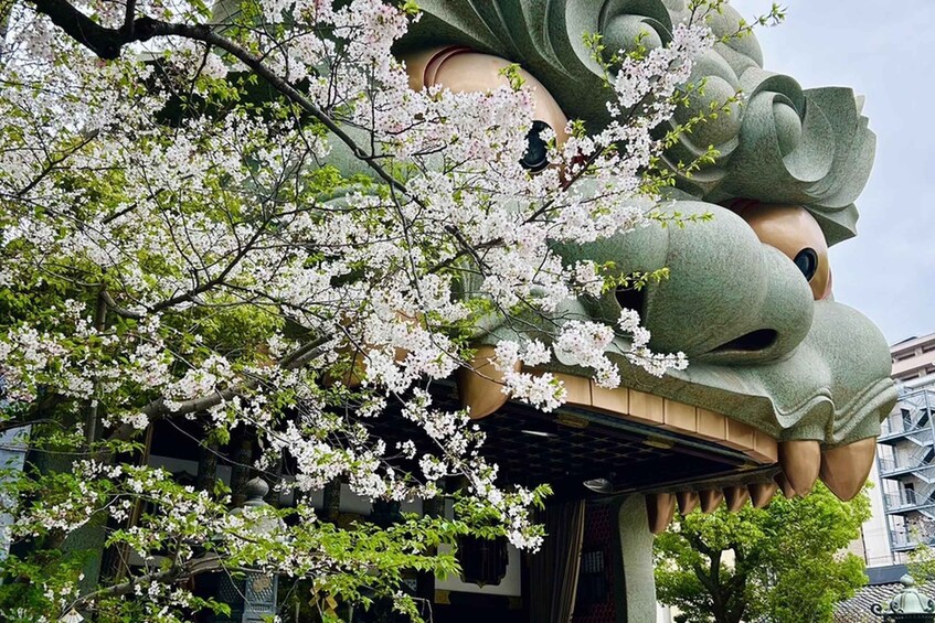 A building with a large, green, dragon-like sculpture and cherry blossoms in the foreground. 5