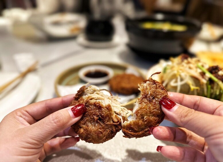 A person holding a fried food item with a crispy exterior. 2