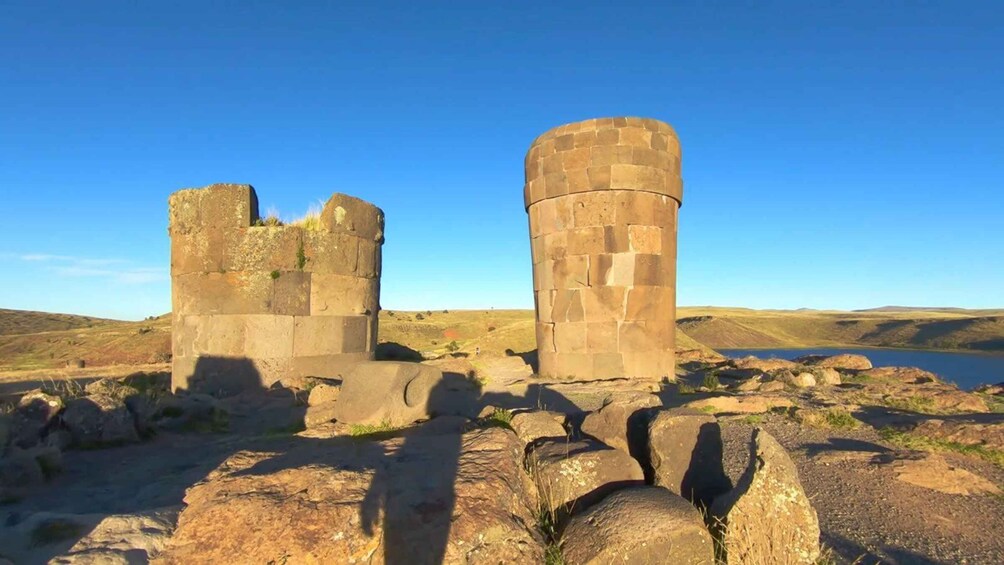 Ancient stone ruins with a clear sky and a lake in the background. 2