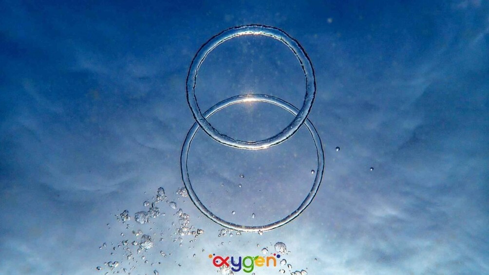 Two clear glass rings floating above water with bubbles around them. 4