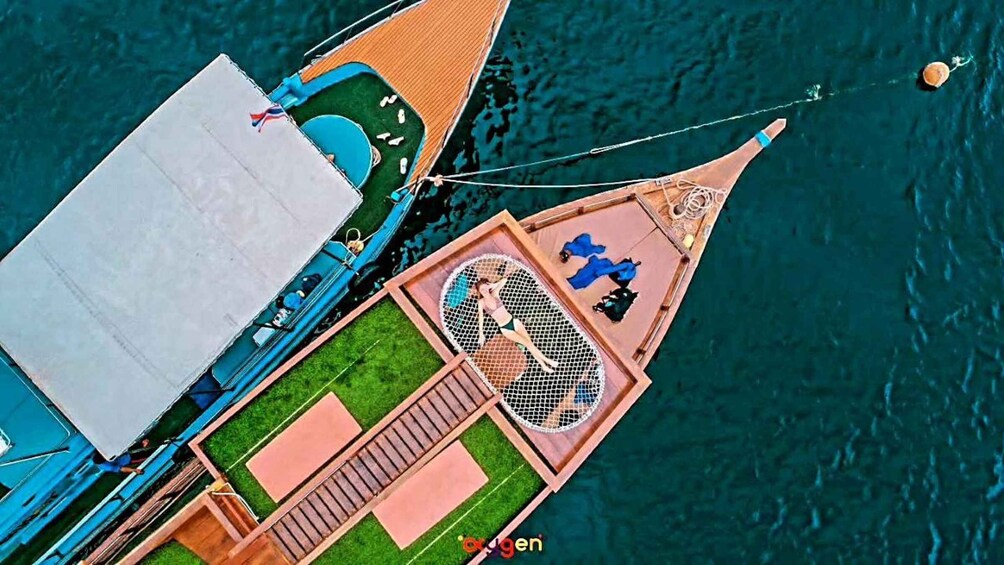 A boat with a covered deck, lounge chairs, and a netted area for sunbathing. 2