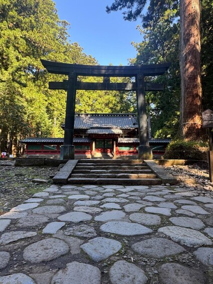 A traditional Japanese torii gate leading to a shrine with a tiled roof. 2