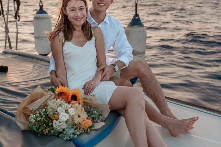 A couple sitting on a boat with a bouquet of flowers. 2
